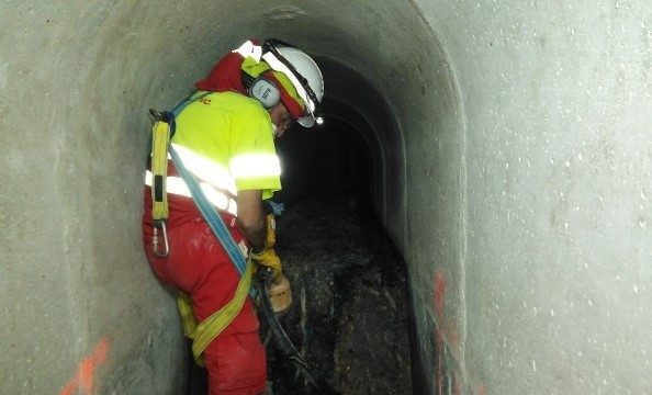 operario realizando trabajo en una colector transitable, en una espacio confinado