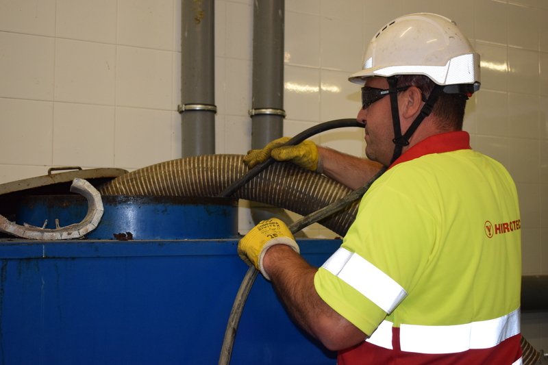 Operario actuación de mantenimiento, extrayendo residuos líquidos para luego transportar residuos peligrosos